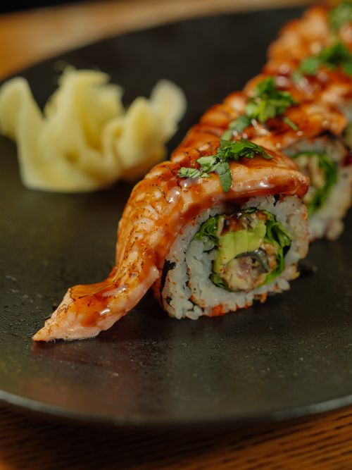 Free Close-up of a salmon sushi roll with avocado and garnish, perfect for food enthusiasts. Stock Photo