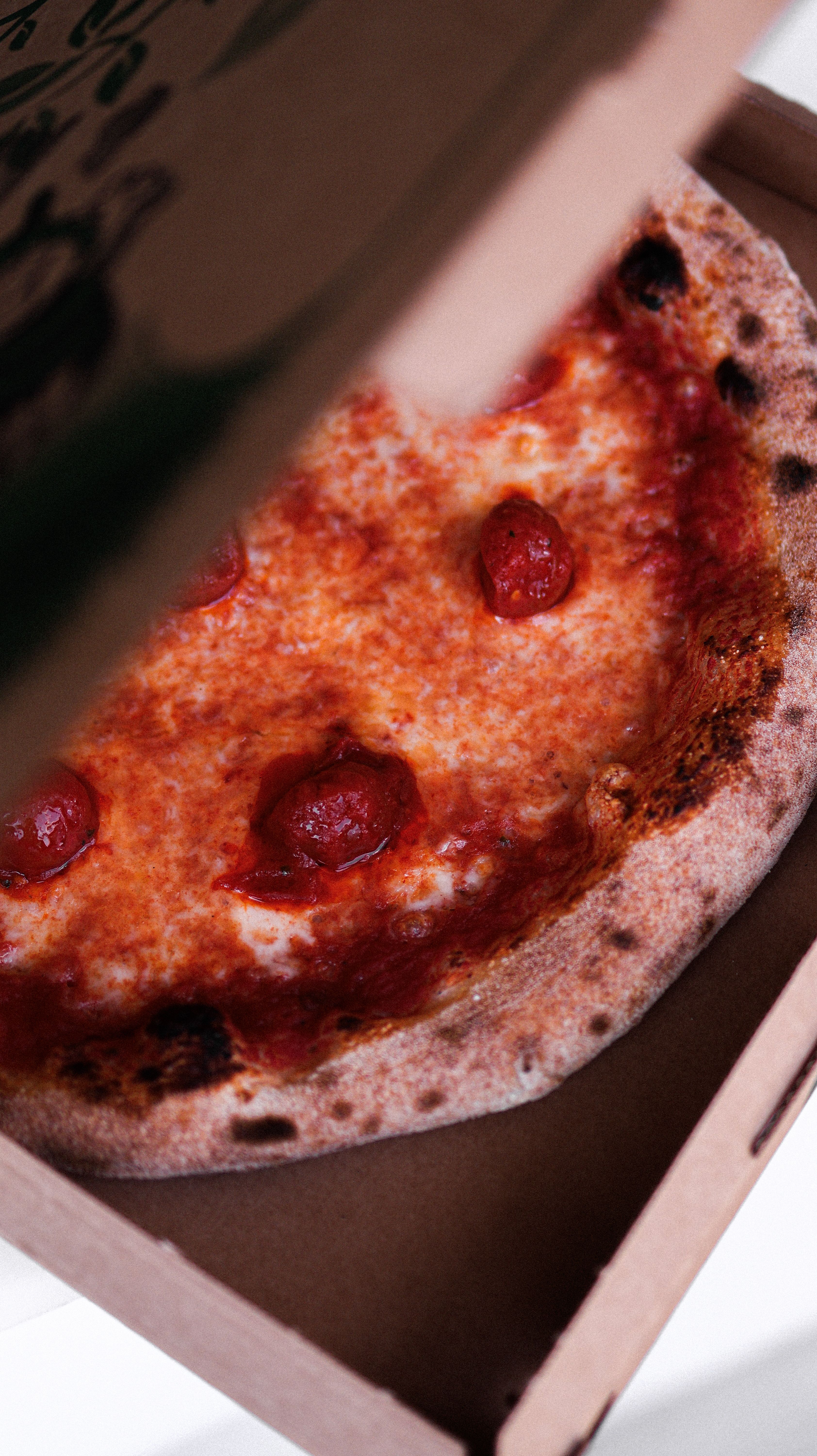 Close-up of a hot pepperoni pizza fresh out of the oven in a delivery box.