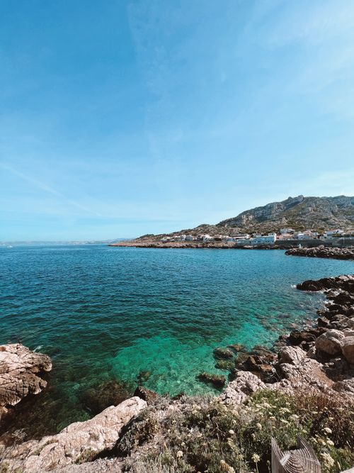 Free A stunning view of a rocky seashore and blue ocean under a clear sky. Stock Photo