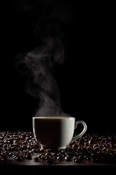 A steaming cup of coffee surrounded by beans on a dark background, creating a warm, inviting mood.