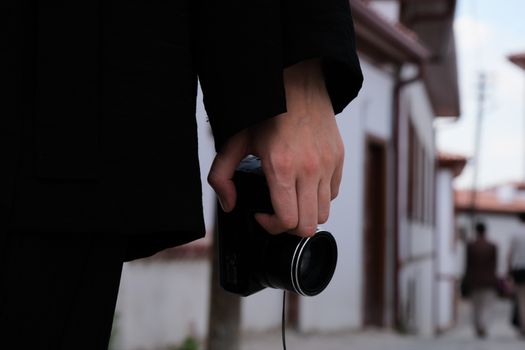 Close-up of a person holding a camera in an urban setting, capturing street life.