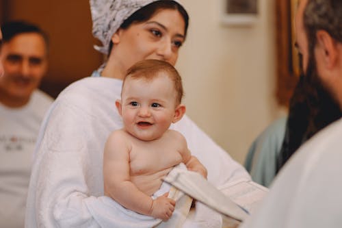 Woman Holding Her Baby during Baptism 