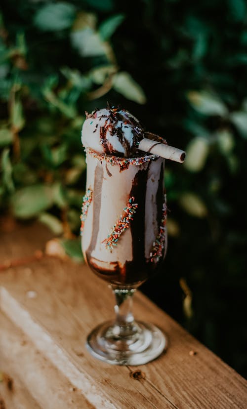 Glass of Chocolate Milkshake with Ice Cream Standing on a Wooden Handrail