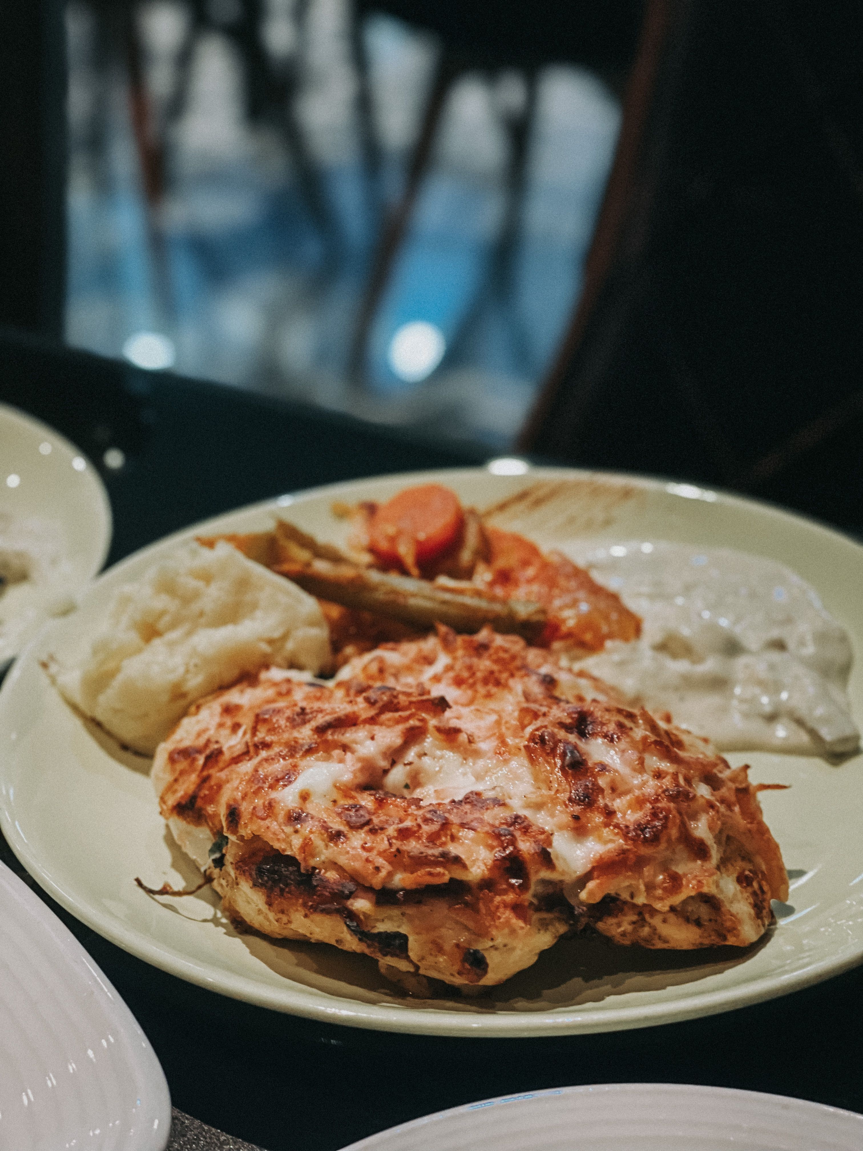 Appetizing roasted chicken served with creamy gravy and vegetables on a plate.