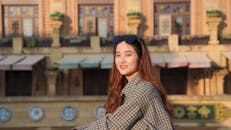Young Woman Sitting Outside in City and Smiling