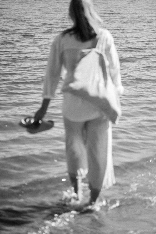 Woman with Bag Walking on Sea Shore in Black and White
