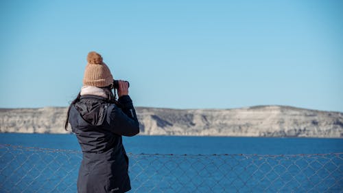 Woman in Jacket Standing with Binoculars on Sea Shore