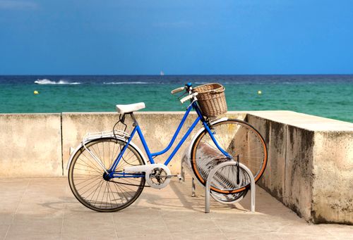 Free A blue bicycle parked by the seaside in Cala Millor, Spain, on a sunny day. Stock Photo