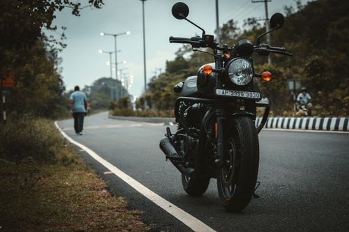 Free A black motorcycle parked on a rural road with ambient light, captured during daylight. Stock Photo
