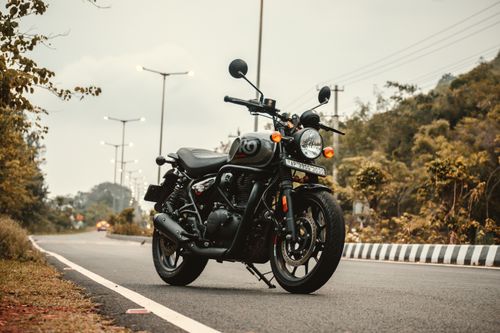 Free A vintage motorcycle parked on a winding road surrounded by autumn foliage, epitomizing freedom and adventure. Stock Photo