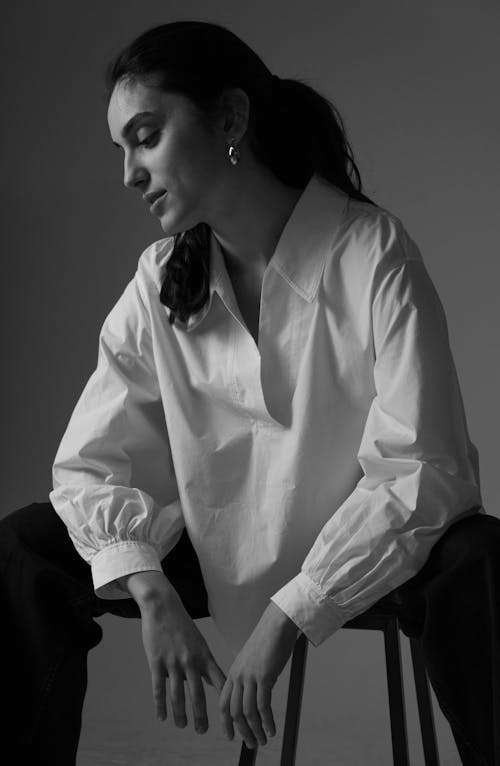 Model in a White Blouse Sitting on a Stool