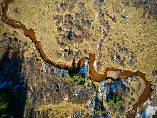 Free Aerial view of a winding river through a rugged, snow-dusted landscape in Colorado. Stock Photo