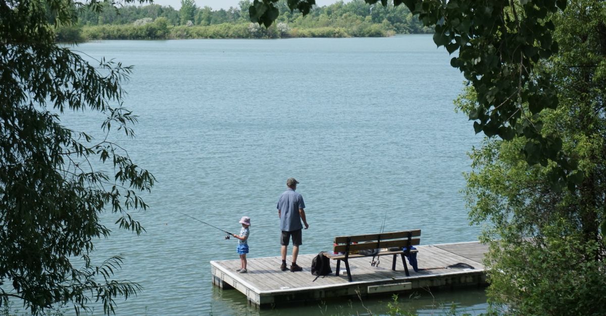 Ojciec z corka wedkujacy na pomoscie nad jeziorem