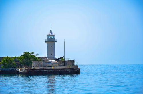 Free Serene view of a lighthouse by the sea, ideal for travel inspiration and coastal scenery imagery. Stock Photo