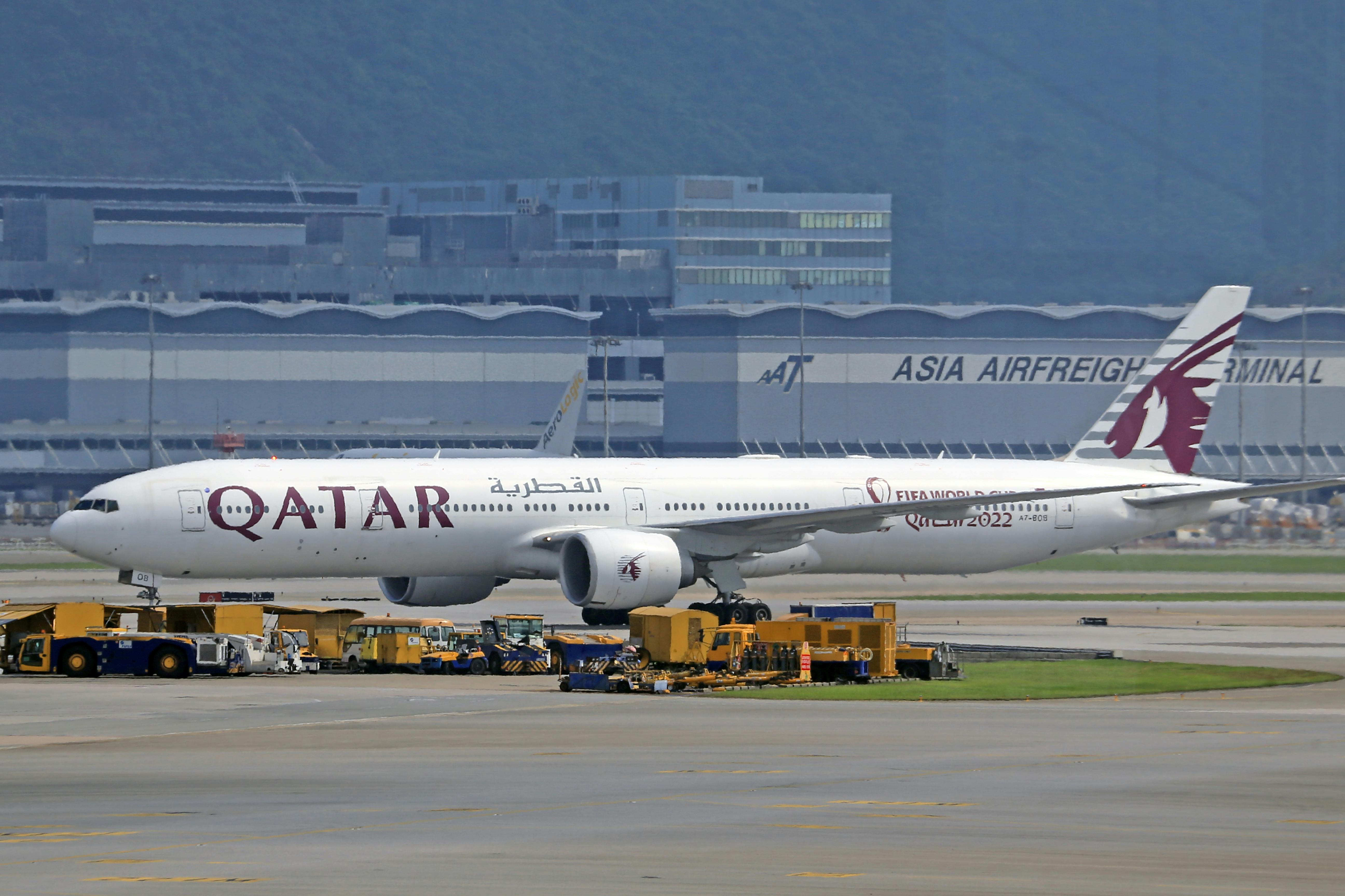 Side view of a Qatar Airways Boeing 777 parked at a busy airport terminal, showcasing transportation.