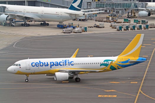 Cebu Pacific plane taxiing on a busy airport runway, ready for takeoff.