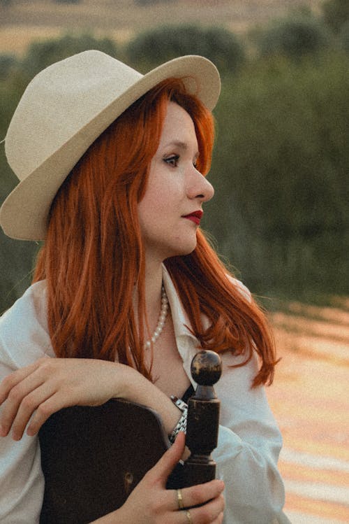 Young Redhead Wearing a Hat Sitting Outside and Looking Away