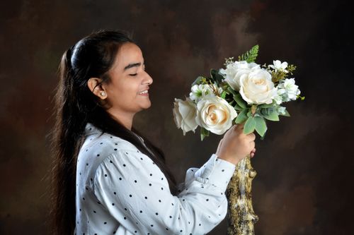 Free A woman joyfully holds a bouquet of white roses against an artistic backdrop. Stock Photo