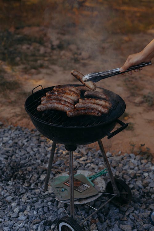 A Person Flipping Sausages on the Grill 