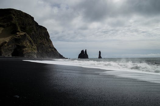 Captivating view of Iceland's black sand beach with towering sea stacks and crashing waves.