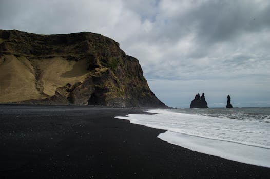 Stunning view of Iceland's black sand beach with rocky sea stacks and dramatic cliffs.