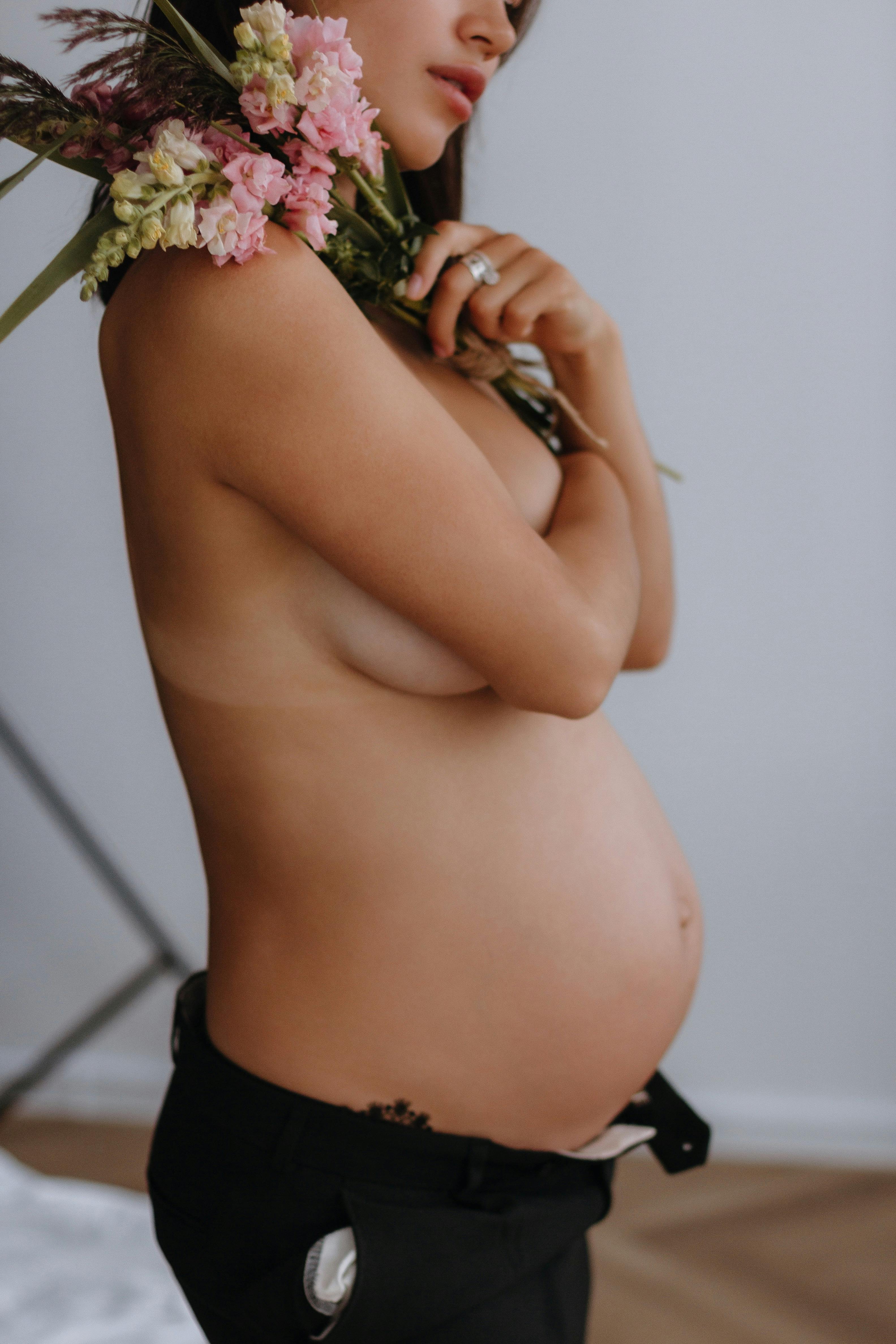 Nude Pregnant Woman Sitting on the Bed with Flowers · Free Stock Photo