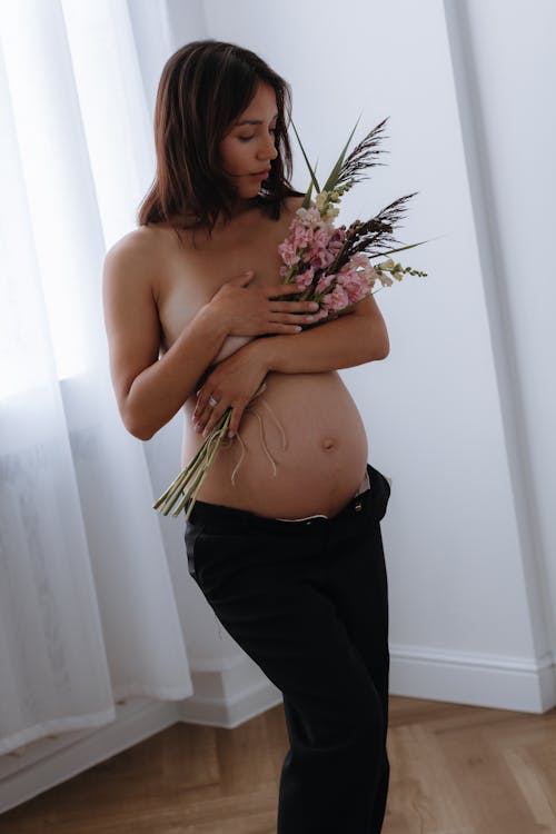 A Topless Pregnant Woman Covering Herself with Flowers