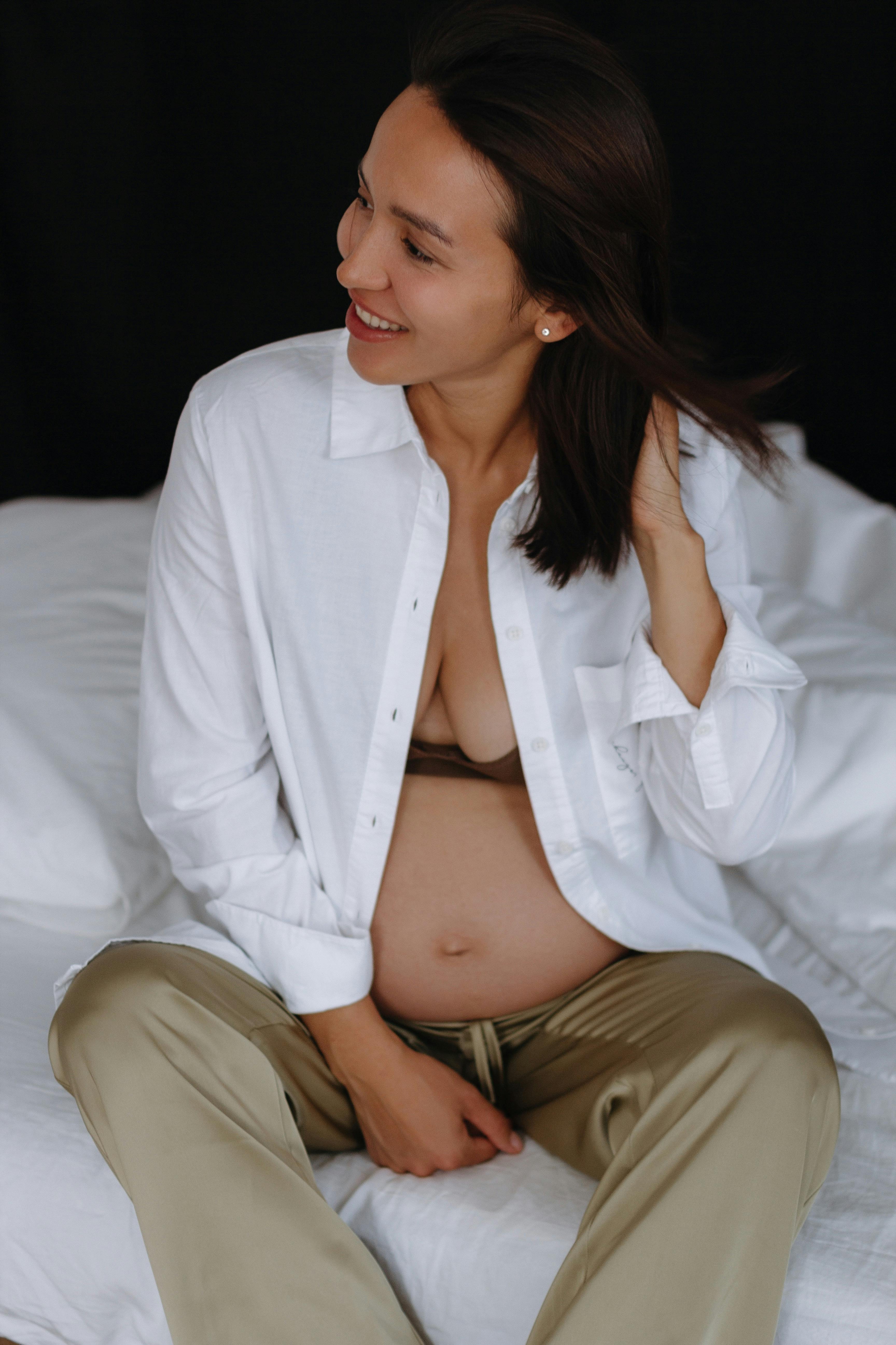 Beautiful Young Woman In White Undershirt Is Holding A Pregnancy