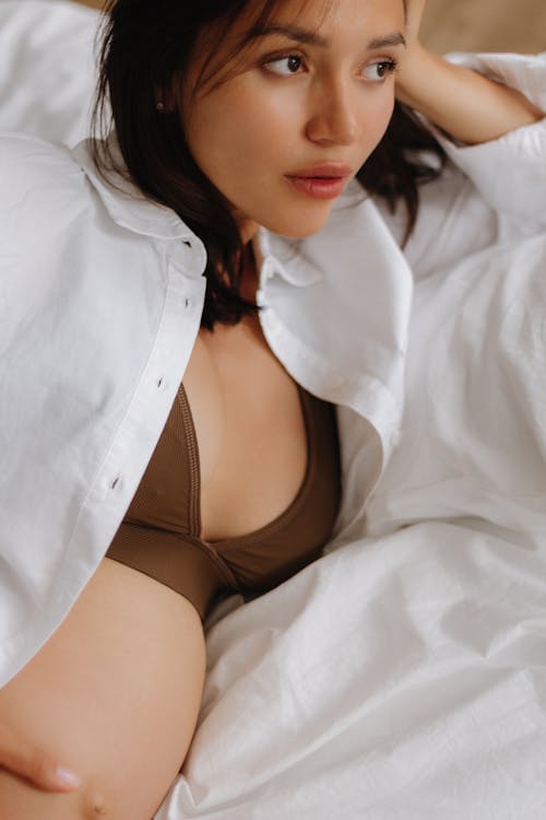 Pregnant Brunette Woman in White Shirt Lying in Bed