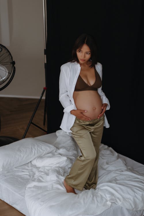 Pregnant Woman in a White Shirt Posing in Studio 