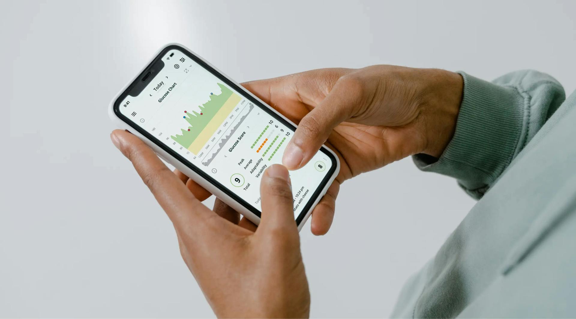 Close-up of hands holding a smartphone showing a health tracking app with charts and data.