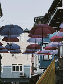 An artistic display of umbrellas hanging above a lively urban alley.