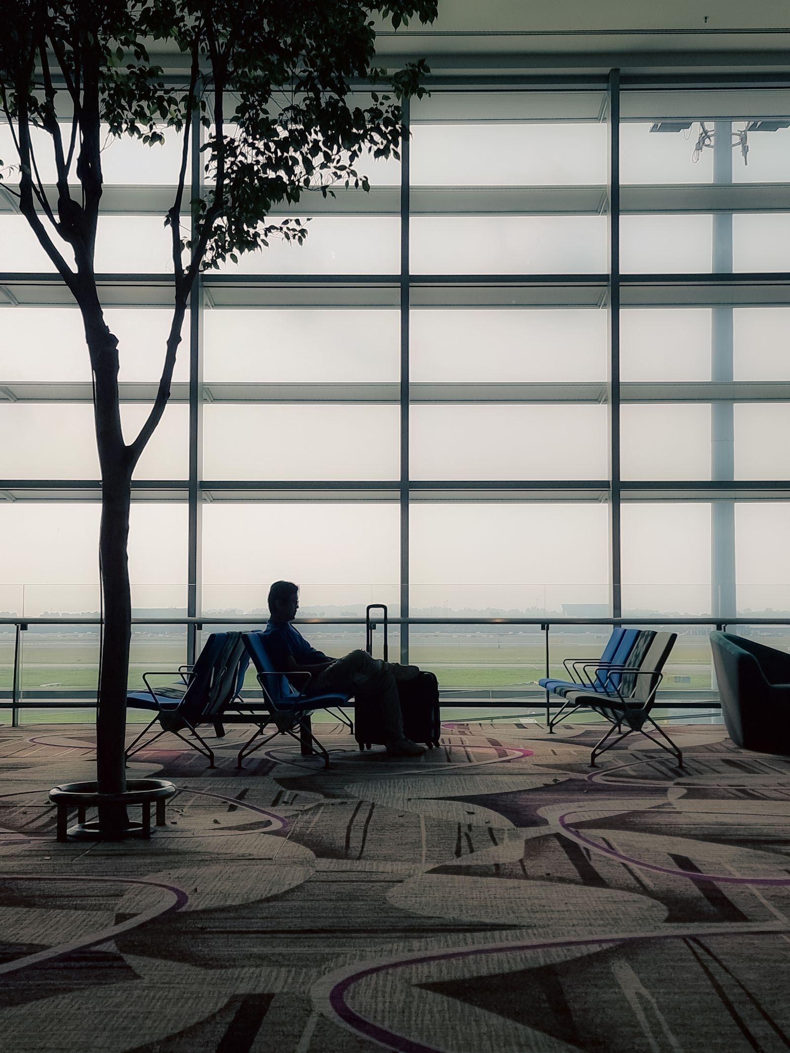 Business traveller with a suitcase seated alone in an airport lounge