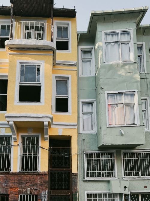Free Close-up of colorful urban townhouses with weathered facades and bay windows, showcasing urban architecture. Stock Photo