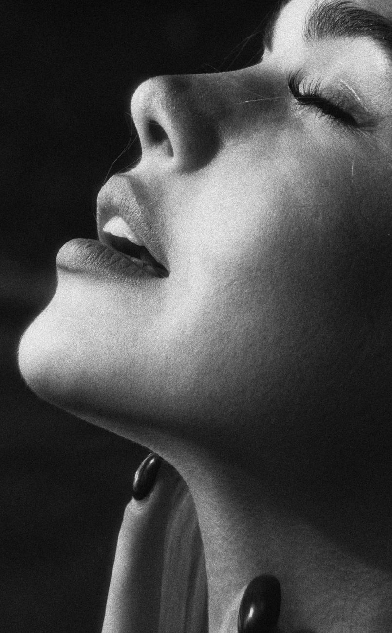 Close-up black and white portrait of a woman with eyes closed, showing serene expression.