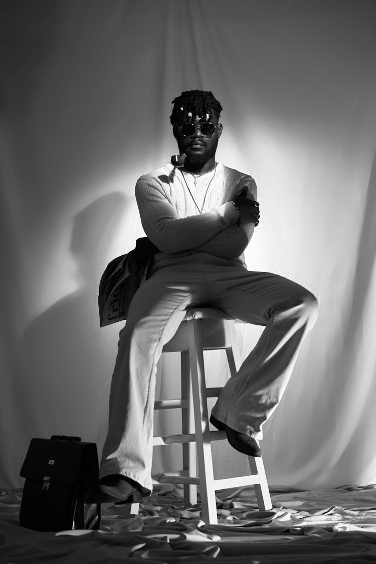 Man With Pipe In Mouth Sitting On White High Stool