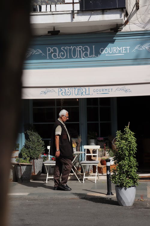 Free Elderly Man Walking Pass the Cafe in City  Stock Photo