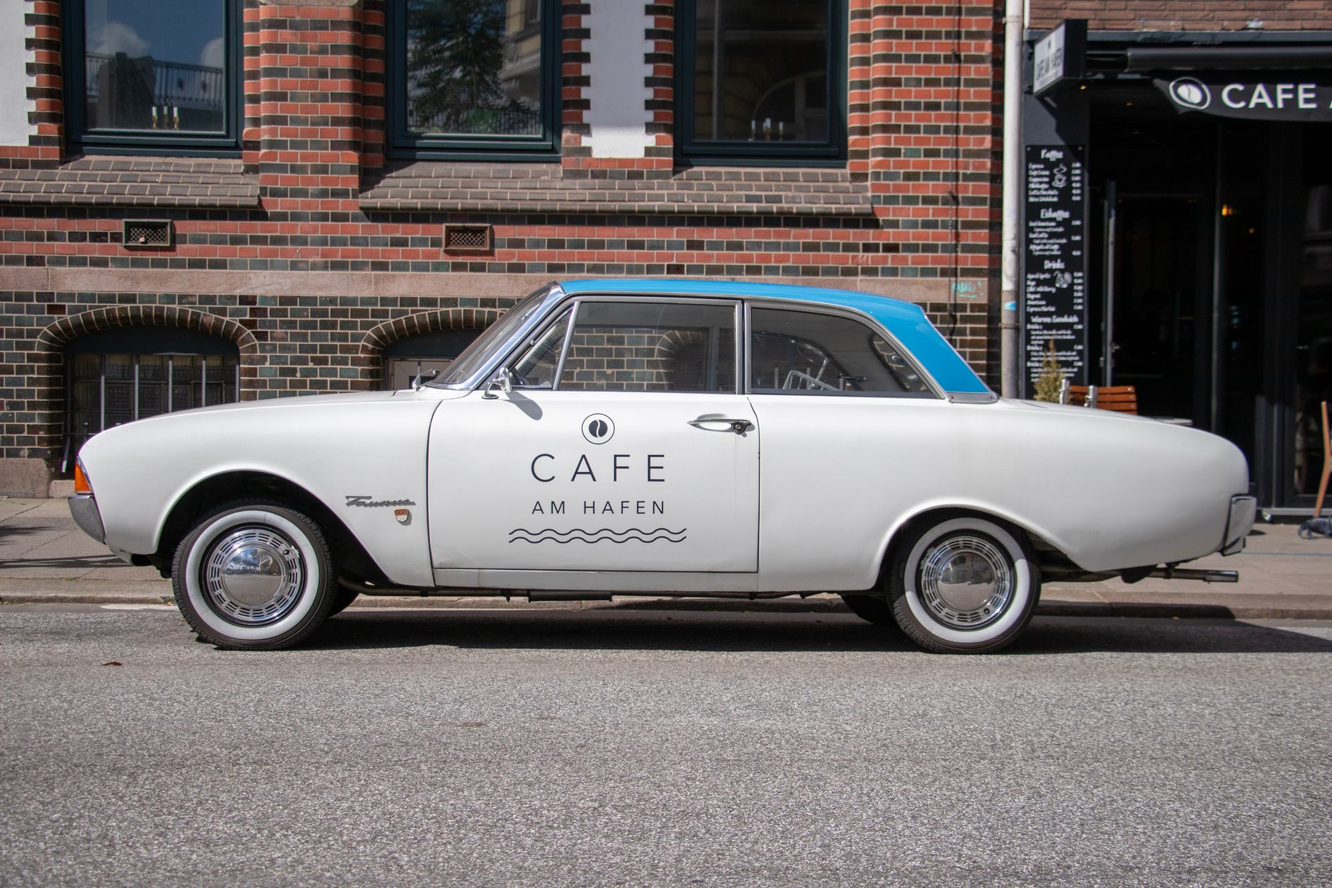Vintage car parked in Hamburg near Cafe Am Hafen, capturing city life.