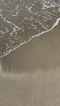 Tranquil scene of ocean waves gently touching a sandy beach shore, perfect for relaxed themes.