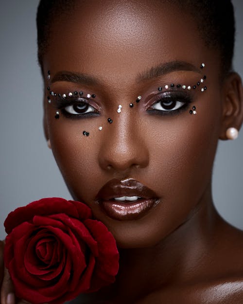 Portrait of a Beautiful Woman Wearing a Creative Makeup Look and Holding a Red Rose 
