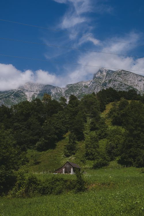Free Serene cabin nestled in verdant valley with majestic mountains in the background. Stock Photo