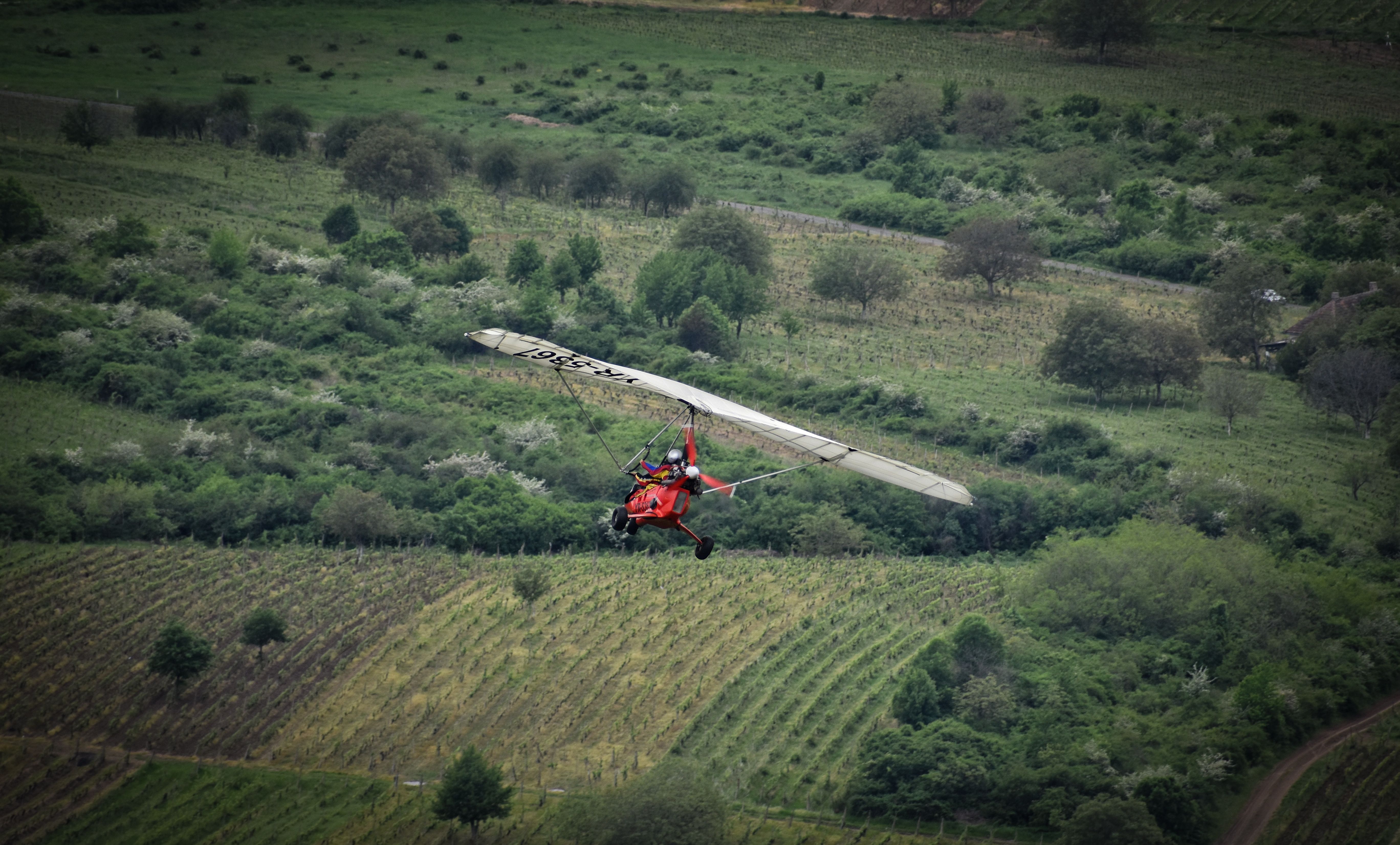 Ultralight aircraft soaring over lush green fields. Aerial adventure captured beautifully.