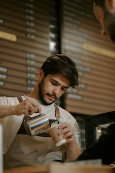 A barista crafting a latte at a café in Baku, showcasing skilled pouring technique.