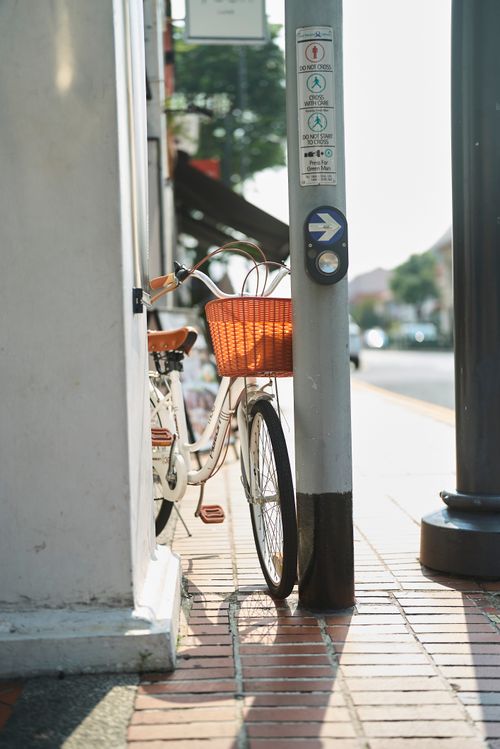 Free A bicycle leaning against a pole on a sunny sidewalk in Singapore, capturing urban life. Stock Photo