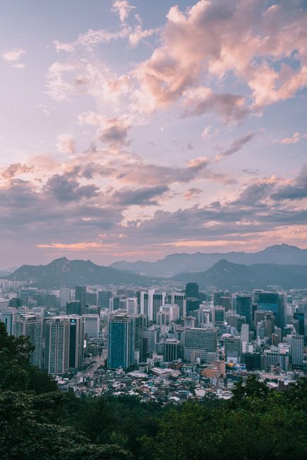Discover Seoul's enchanting cityscape against a backdrop of rolling mountains at twilight.