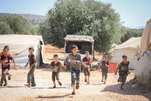 Boys Smiling and Playing near Tents