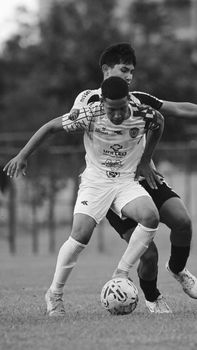 Two soccer players compete fiercely for the ball during a match.