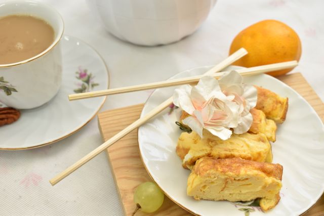 Delicate breakfast arrangement featuring a warm cup of coffee and a fluffy omelette served with chopsticks.