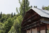 Rustic chalet with wooden balconies nestled in a lush forest in Puy-Saint-Vincent, France.