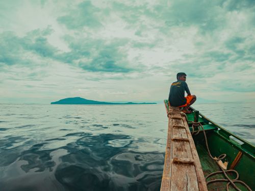 Free A teenager on a wooden boat in the ocean near Batangas, Philippines. Stock Photo